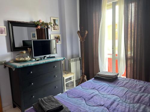 a bedroom with a bed and a dresser with a tv on it at Villino con giardino a 10 minuti a piedi dal mare e vicino a Roma in Torvaianica
