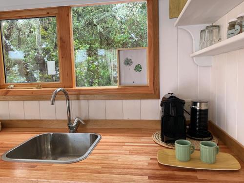 a kitchen sink with two cups on a cutting board at Mágica Tiny House con vista a la Montaña in San Martín de los Andes