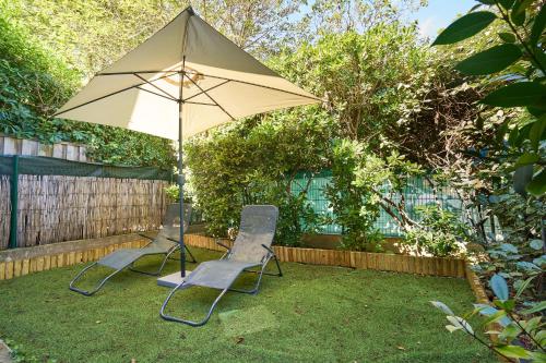 2 chaises et un parasol dans la cour dans l'établissement Maison climatisée, jardin , et parking privatif proche centre ville, à Avignon