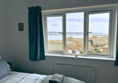 a bedroom with a window with a view of the ocean at Chalkhill View - Idyllic Sea Views Parking in Wyke Regis