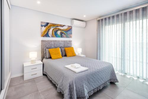 a bedroom with a bed with yellow pillows and a painting at Kasino II 3ºI in Monte Gordo