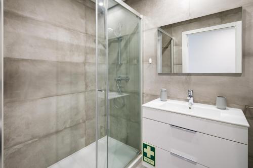 a bathroom with a shower and a sink and a mirror at Kasino II 3ºI in Monte Gordo