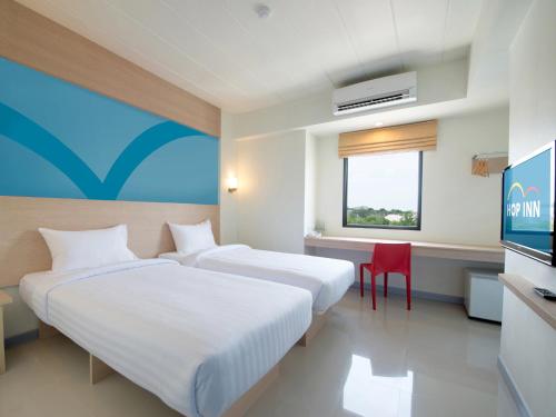 a hotel room with two beds and a television at HOP INN Trang in Trang