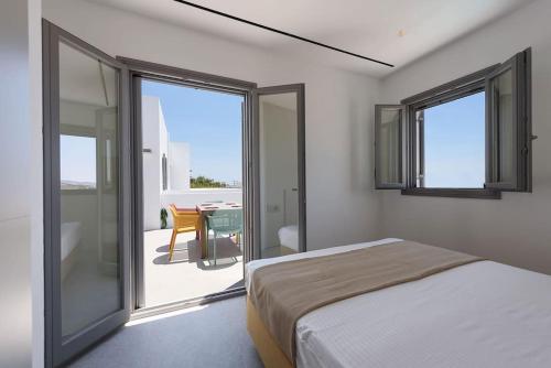 a bedroom with a bed and a balcony with a table at OneAlyki in Aliki