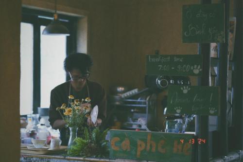 a woman standing behind a counter with flowers at Maison de Hill Home in Dồng Văn