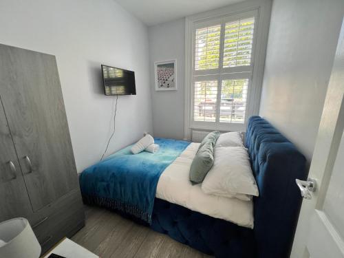 a bedroom with a bed with blue sheets and a window at Linden Garden apartment in Bedford