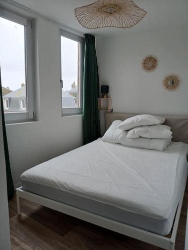 - une chambre avec un lit doté de draps blancs et 2 fenêtres dans l'établissement Appartement avec beau balcon, à Mers-les-Bains