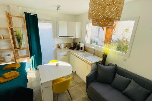 a kitchen with a couch and a table in a room at Studio cocooning Jeanne au calme avec terrasse in Romans-sur-Isère