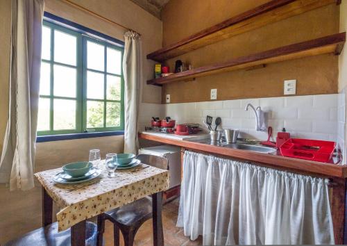 eine Küche mit einer Spüle und einer Theke mit einem Tisch in der Unterkunft Cafezal em Flor Turismo e Cafés Especiais in Monte Alegre do Sul