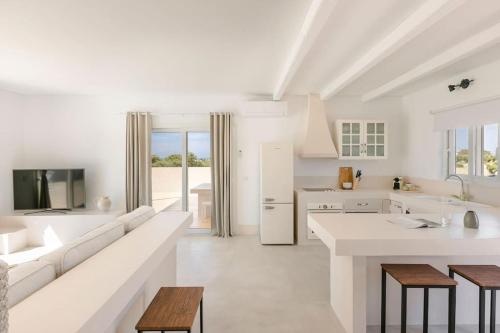 a white living room with a white couch and a kitchen at Villa Lotus - Ionian Villa Collection in Lixouri