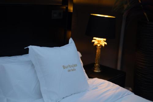 a bed with a white pillow next to a lamp at burbujas del sella in Ribadesella