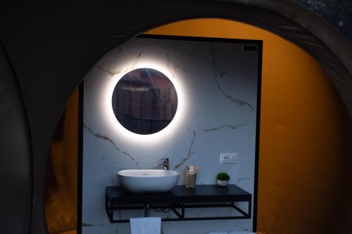 La salle de bains est pourvue d'un lavabo et d'un miroir rond. dans l'établissement burbujas del sella, à Collera