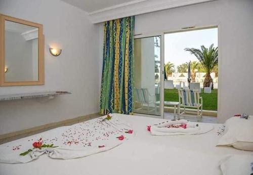 a bedroom with a large white bed with flowers on it at KhimA XL in Hammamet Sud