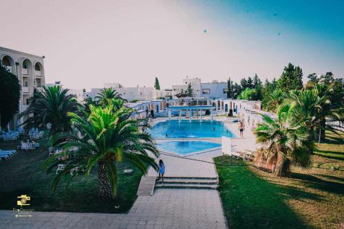 a large swimming pool with palm trees in front of a building at KhimA XL in Hammamet Sud