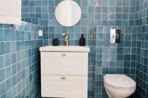 La salle de bains est pourvue de carrelage bleu, de toilettes et d'un lavabo. dans l'établissement Andromède, villa de charme avec vue et accès mer, au Pradet