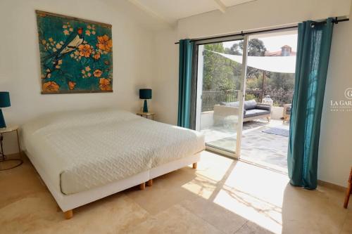 une chambre avec un lit et une grande fenêtre dans l'établissement Andromède, villa de charme avec vue et accès mer, au Pradet