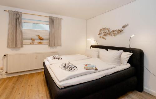 ein Schlafzimmer mit einem Bett mit weißer Bettwäsche und einem Fenster in der Unterkunft Hüs Wüf im Haus Ornum in Westerland