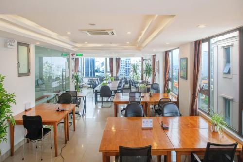 un restaurante con mesas y sillas de madera y ventanas en Waikiki Beach Hotel, en Da Nang