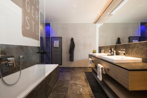 een badkamer met een wastafel, een bad en een douche bij DAS GERSTL Alpine Retreat in Malles Venosta