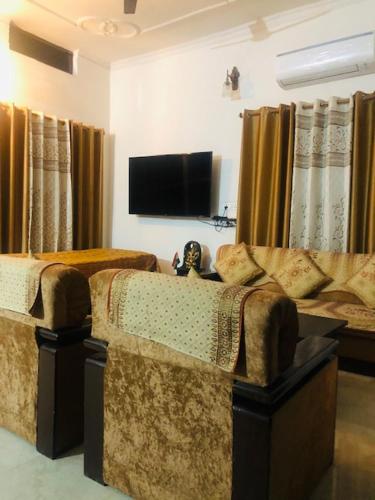 salon z 2 krzesłami i telewizorem z płaskim ekranem w obiekcie Tattva Luxurious Apartment w mieście Waranasi