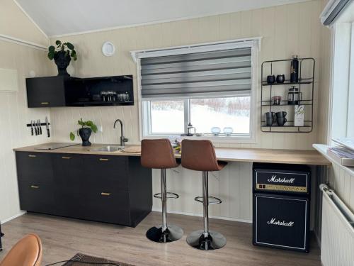 a kitchen with a sink and two bar stools at Veigakot in Akureyri
