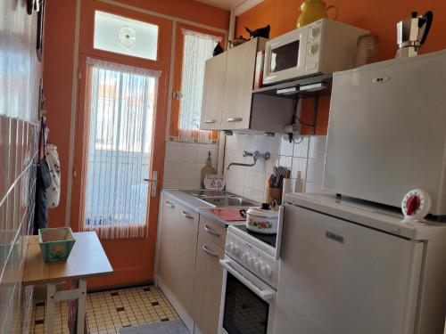 Il comprend une cuisine équipée d'un réfrigérateur blanc et d'une cuisinière. dans l'établissement Les Pampres, à Saint-Jean-de-Monts