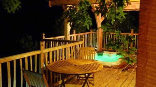 a table and chairs on a deck with a swimming pool at Cabane-hobbit de Samsaget in Eyvignes-et-Eybènes