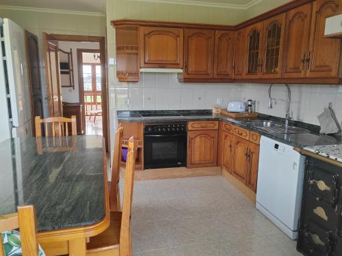 a kitchen with wooden cabinets and a black counter top at El Rancho Busto - Luarca in Busto