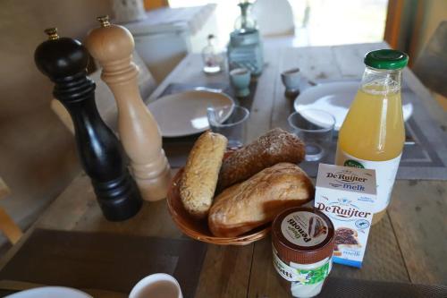 a table with a bowl of bread and a bottle of orange juice at Luxe en romantische overnachting 4 personen Grumpy in Behelp