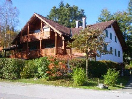 a large wooden house with a porch and a tree at Ferienwohnungen Steigmühlenweg in Hinteregg