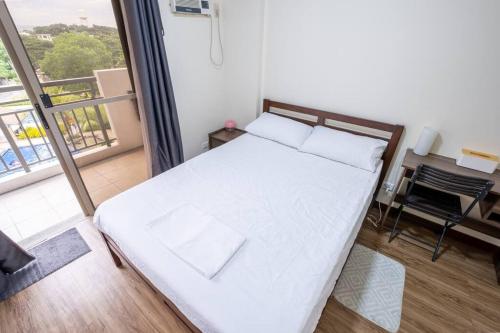 a white bed in a room with a balcony at 2BR Fully Air-Conditioned Staycation PLUS Free Parking in Manila