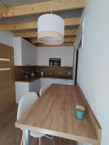 a kitchen with a wooden table and white cabinets at Stania Scandinavian CENTRUM in Boszkowo-Letnisko