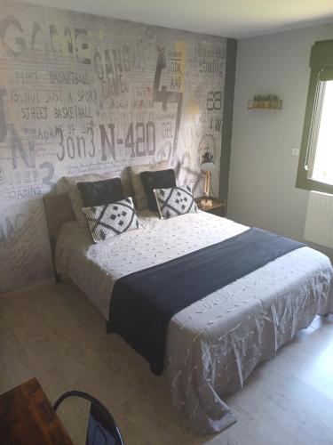 ヴォンダン・ル・ヴィエイユにあるChambre d'hôtes "Sur la route des Terrils"のベッドルーム1室(ベッド1台付)、壁に落書きが備わります。