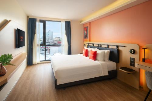 a hotel room with a bed and a large window at Lumen Bangkok Udomsuk Station in Bangkok