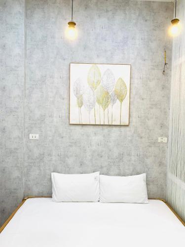 a bedroom with a white bed and a painting on the wall at Primrose Homestay Cao Bang in Cao Bằng