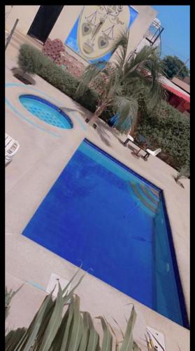 ein blauer Pool neben einem Gebäude in der Unterkunft Hotel Al Khayatt in Kaolack