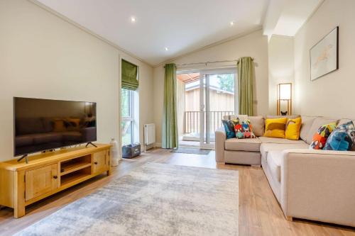 a living room with a couch and a flat screen tv at Campden Lodge 1 in Kingham