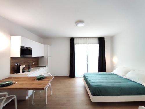 1 dormitorio con cama, mesa y cocina en Residence Cala Bianca en Porto Torres