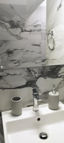 a bathroom with a white sink with a painting on the wall at Sevilia Rooms in Qeparo