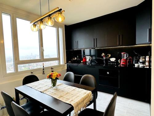 une salle à manger avec une table et une cuisine avec des armoires noires dans l'établissement Appartement Luxueux avec vue dégagée panoramique sur PARIS et alentours, à Châtillon