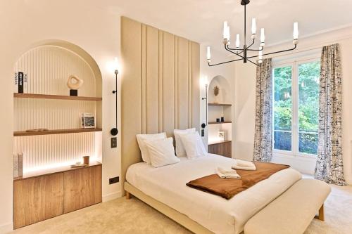 - une chambre avec un grand lit et un lustre dans l'établissement Appartement d'architecte luxueux Neuilly-sur-seine, à Neuilly-sur-Seine