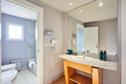 a bathroom with a sink and a toilet and a mirror at Silken Turcosa in Castellón de la Plana