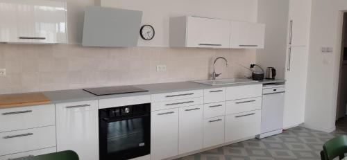 a kitchen with white cabinets and a black appliance at Maison neuve centre Barfleur in Barfleur
