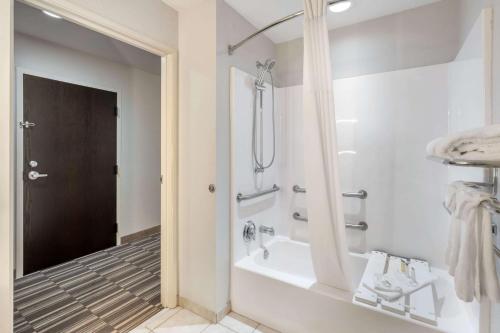 a white bathroom with a tub and a shower at Microtel Inn & Suites by Wyndham Brooksville in Ridge Manor