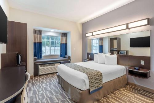 a hotel room with a bed and a television at Microtel Inn & Suites by Wyndham Brooksville in Ridge Manor