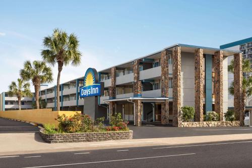 マートルビーチにあるDays Inn by Wyndham Myrtle Beach-Beach Frontのホテルの看板とヤシの木が見えるホテルの外観
