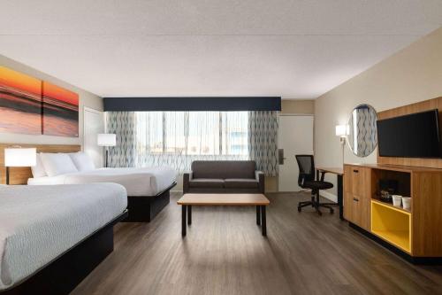 um quarto de hotel com uma cama, um sofá e uma televisão em Days Inn by Wyndham Myrtle Beach-Beach Front em Myrtle Beach