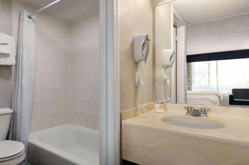 a bathroom with a sink and a toilet and a mirror at Days Inn by Wyndham Myrtle Beach-Beach Front in Myrtle Beach