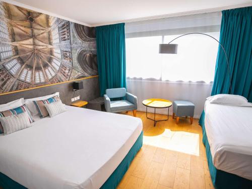 um quarto de hotel com uma cama grande e uma cadeira em Mercure Mont Saint Michel em Monte Saint-Michel