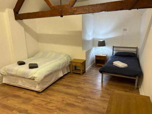 1 dormitorio con 2 camas y mesa con lámpara en The Diary en Takeley